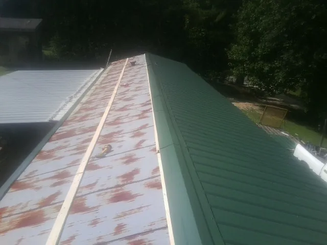 Old rusted panels beside newly installed green metal roofing — Wind Damage Roof Repair by Roofing Brothers in Salisbury Mills
