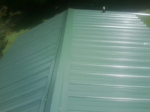 New green metal panels meeting at the ridge of a roof — Flat Roof Repair work by our crew in Salisbury Mills