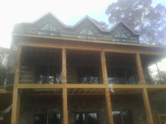 Dormers and porch framing on a large log home under construction — Roof Coating work by our crew in Salisbury Mills