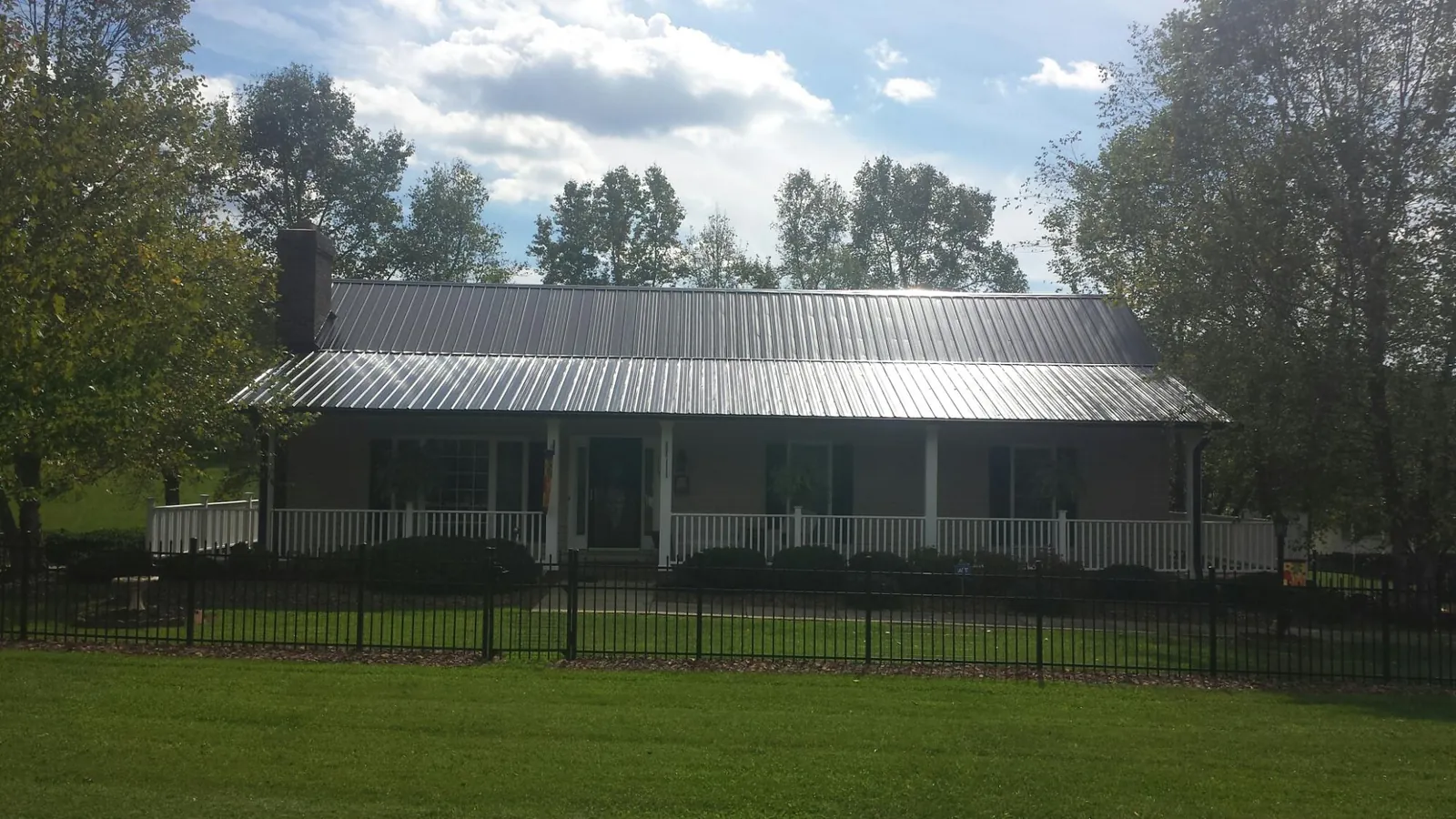 Gray metal roof on a brick ranch with a full width front porch — Gutter Guard Installation work by our crew in Salisbury Mills
