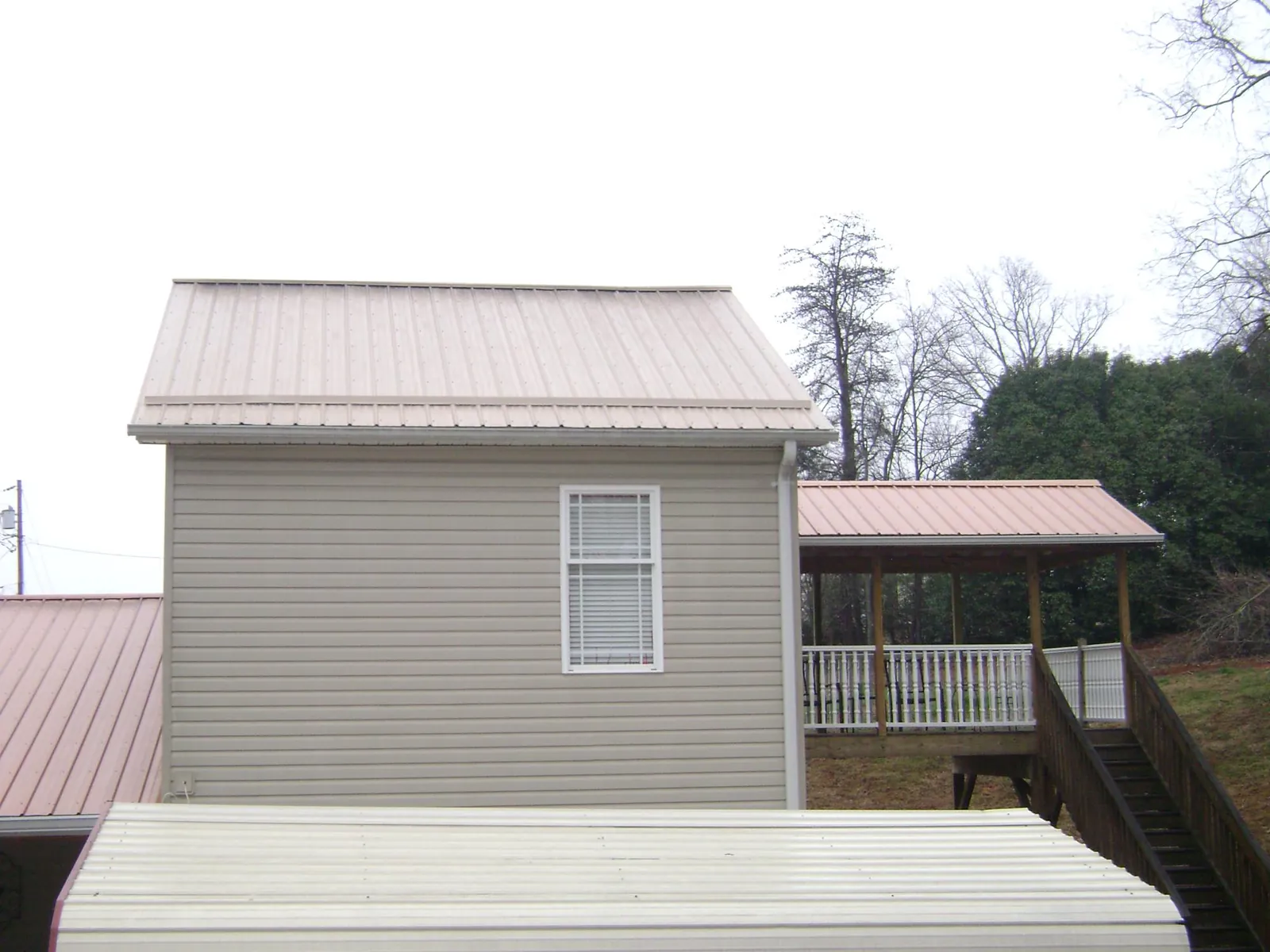 Tan metal roofs on a two story addition and attached porch, from a Roof Replacement job in Salisbury Mills