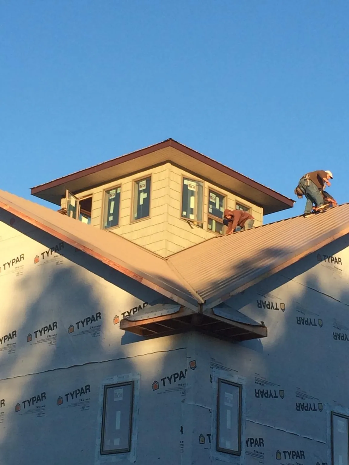 Roofers working around a rooftop cupola on a new metal roof at sunset — Roof Waterproofing in Salisbury Mills by Roofing Brothers